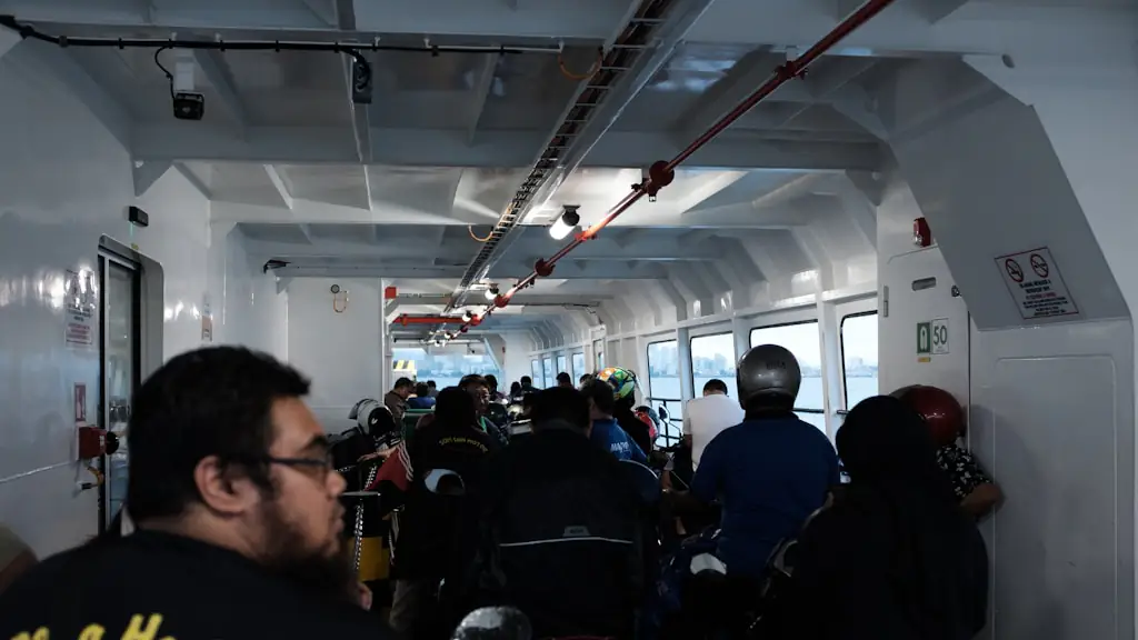 Passengers and parked motorcycles filling the enclosed vehicle deck of a passenger ferry