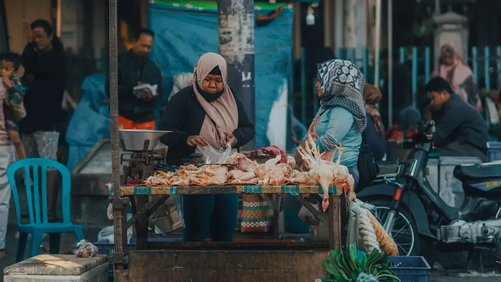 Two women in headscarves weighing fresh fish at an open-air market stall beside the street