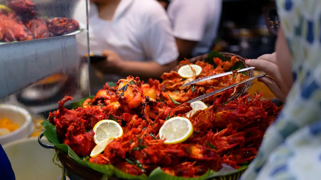 Market food stall serving a large platter of cooked prawns garnished with lemon slices